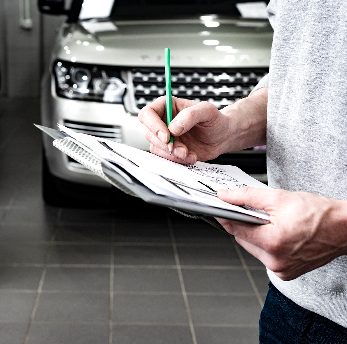 carchex-glossary-hero Person holding a clipboard inspecting a vehicle in a showroom