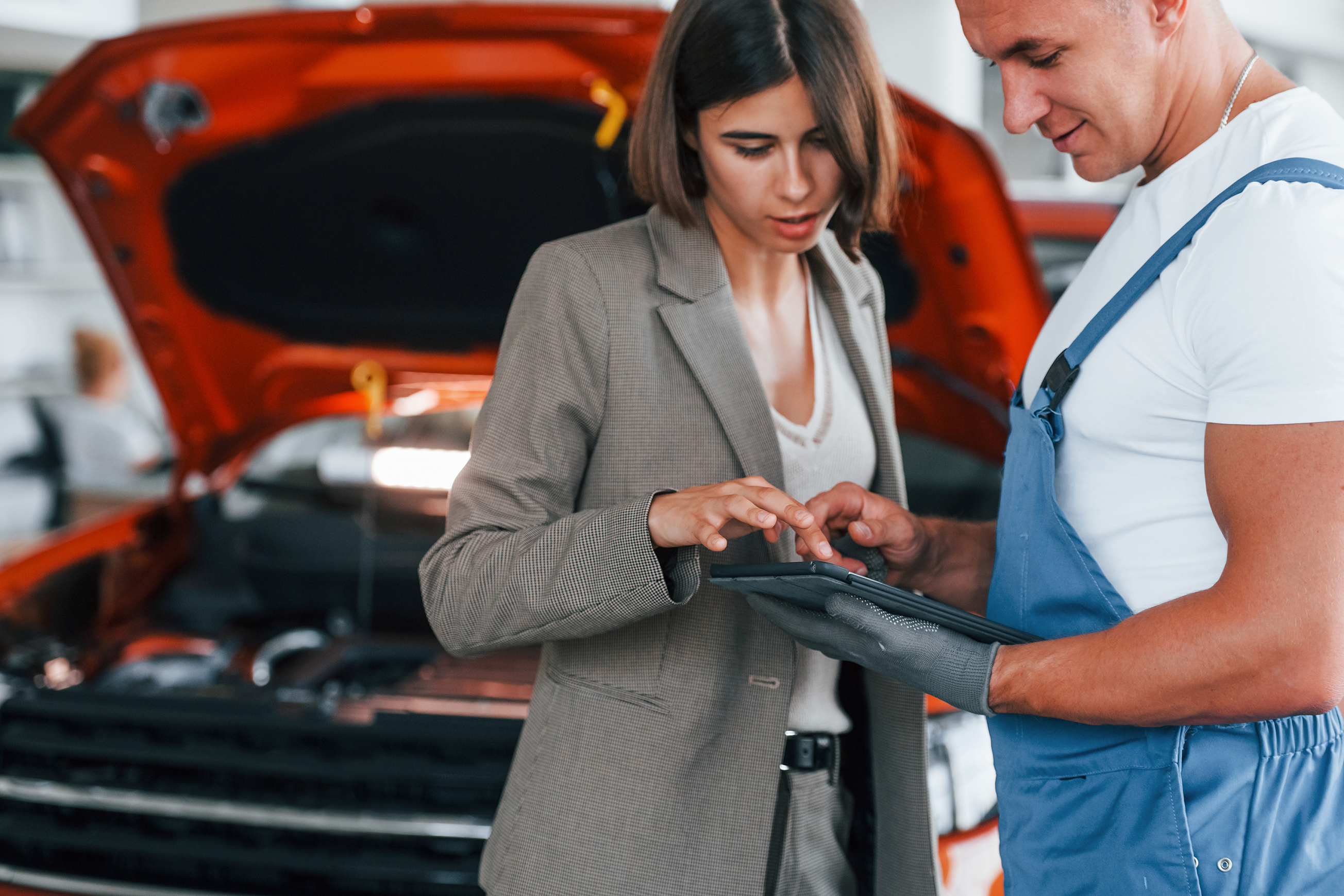 Person holding a clipboard inspecting a vehicle in a showroom